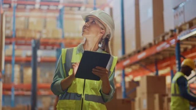 戴着安全帽的专业女工在摆满货架的零售仓库里用数字平板电脑检查库存和库存。在物流配送中心工作的人