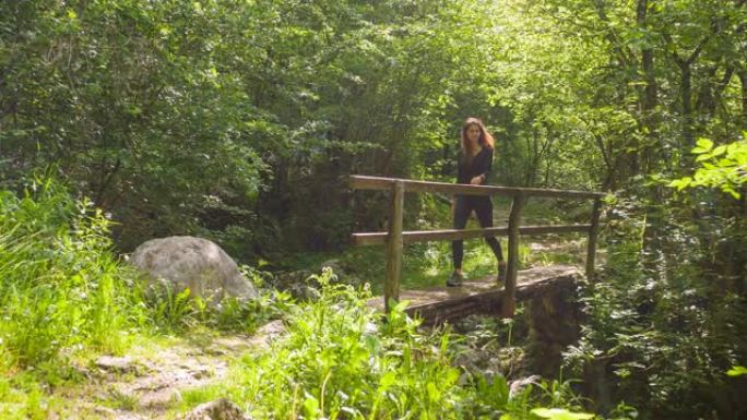 女人在大自然中穿越小木桥在户外徒步旅行