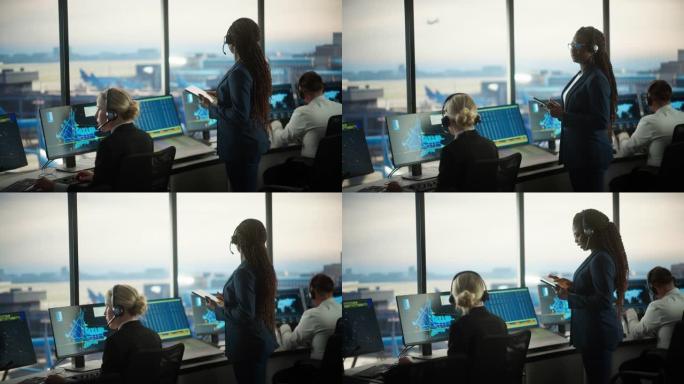 黑人女性空中交通管制员在机场塔楼手持平板电脑。办公室充满了台式计算机显示屏，带有导航屏幕，飞机出发和