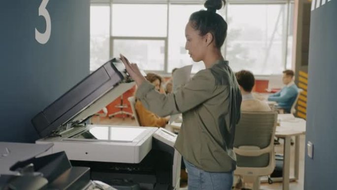 年轻的女商人在办公空间使用多功能复印机