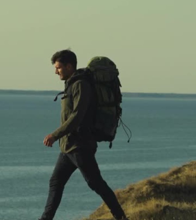 背着背包的男人在海边的山上行走