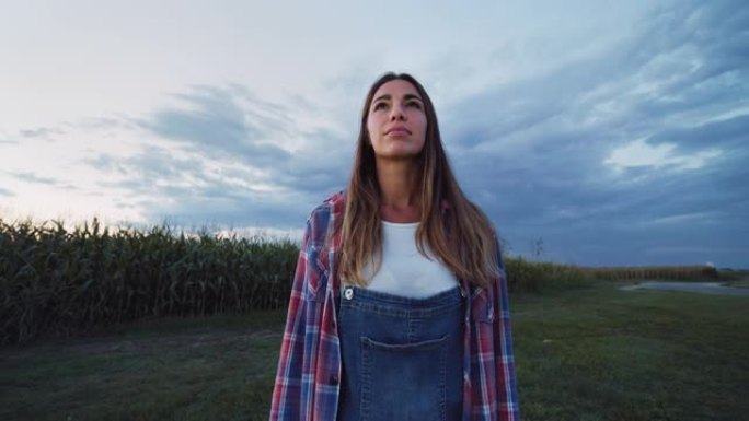 一个女人在绿色的玉米田里微笑着环顾四周的肖像。年轻的女农民欣赏美景，对她的环保小企业感到高兴。农业项
