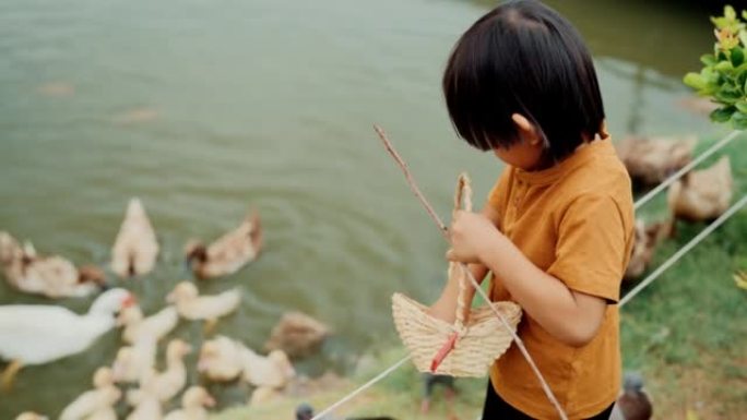 快乐的学龄前男孩和爷爷一起学习喂鸭子。