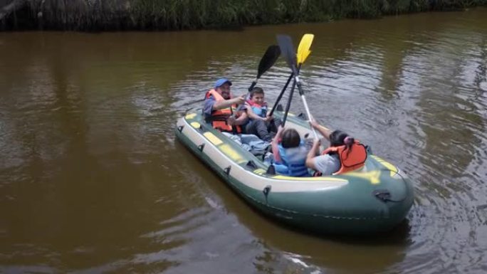 拉丁美洲家庭在木筏上享受阳光明媚的一天，用桨嬉戏品尝