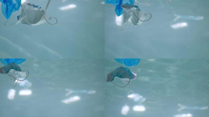 废弃一次性医用口罩在水下。大流行慢动作后，漂浮在海洋中的塑料废物受到污染。