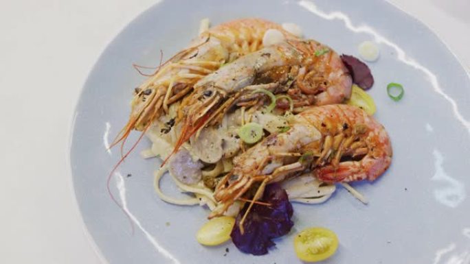 新鲜虾配意大利面和蔬菜放在白色盘子里