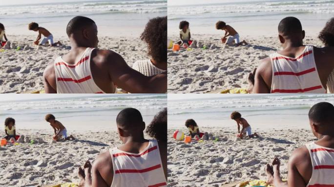 非裔美国儿童在沙滩上玩沙子，他们的父母拥抱