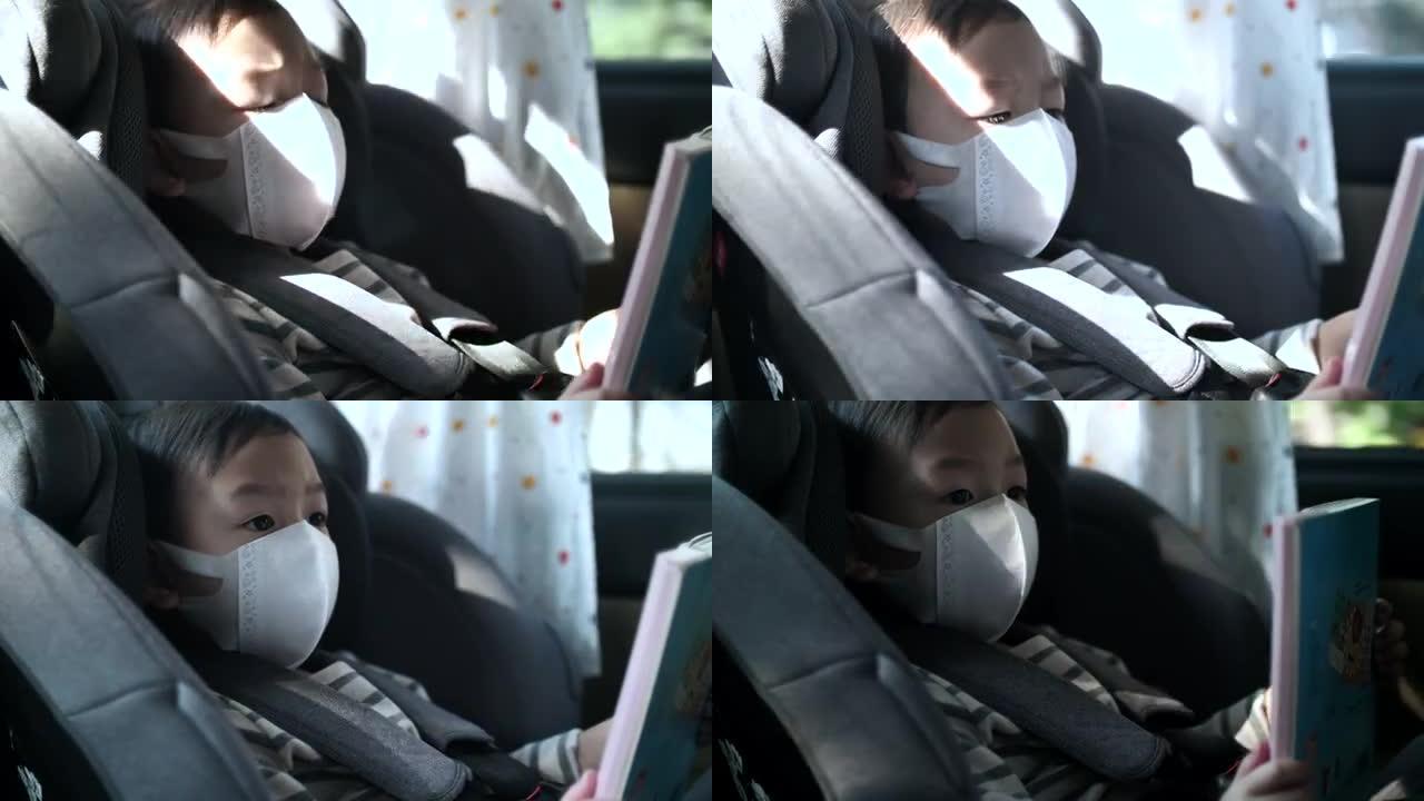 戴着口罩坐在汽车座椅上准备旅行的小男孩