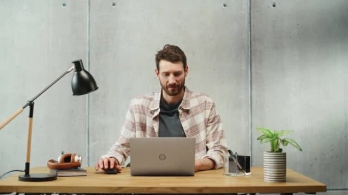 专业的有创造力的人坐在办公室的办公桌前，在笔记本电脑上工作。时尚的办公空间设计非常适合从事电子商务项