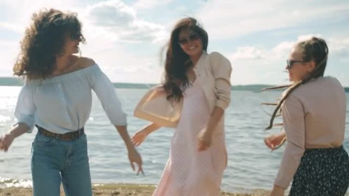 女性朋友穿着时髦的夏装在沙滩上跳舞，一起享受周末