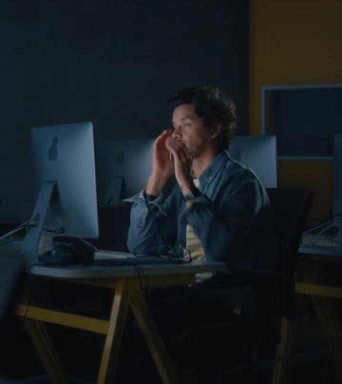 垂直屏幕: 压力大的男学生独自坐在大学信息学室，晚上在计算机科学项目上工作。累了的学者在大学里用电脑