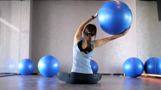 年轻女子与健身房蓝色球
