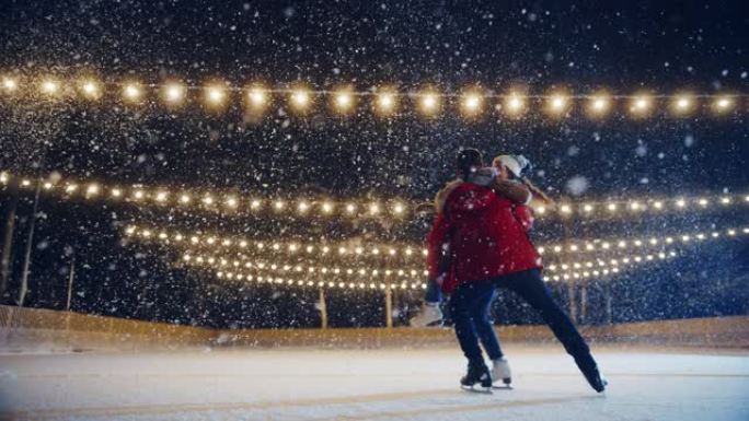 浪漫的冬天下雪的夜晚: 滑冰夫妇在溜冰场上玩得开心。双人滑冰boyfried抬起他美丽的女友并旋转。