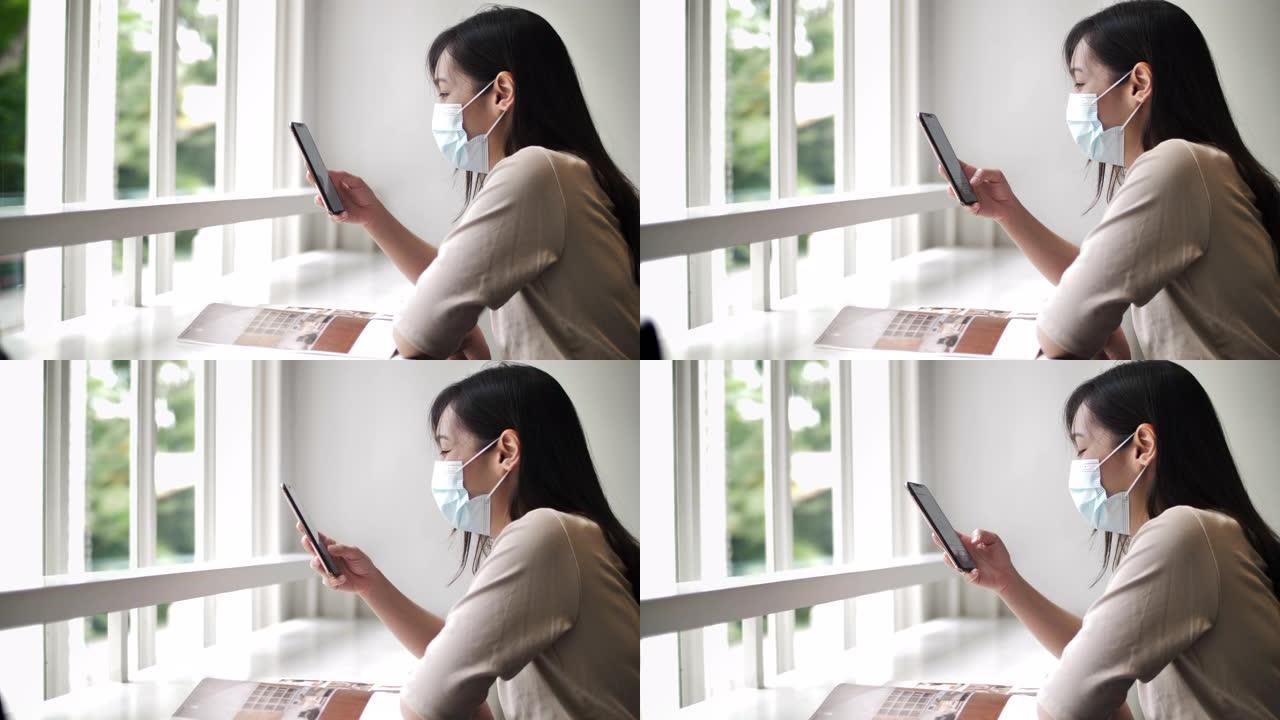 亚洲女性在咖啡馆使用带防护面罩的智能手机