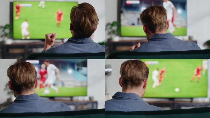 体育迷在家里的电视上观看重要的足球比赛，他用拳头积极地打手势，为自己的球队加油。阁楼公寓舒适的客厅。