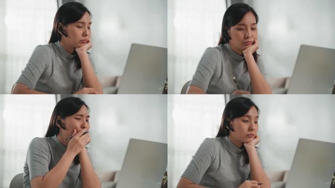 亚洲妇女在家里使用笔记本电脑而苦苦挣扎