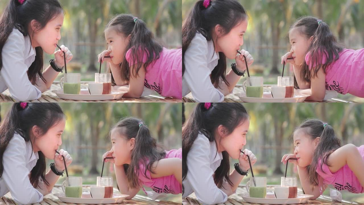 亚洲儿童女孩在公园喝果汁