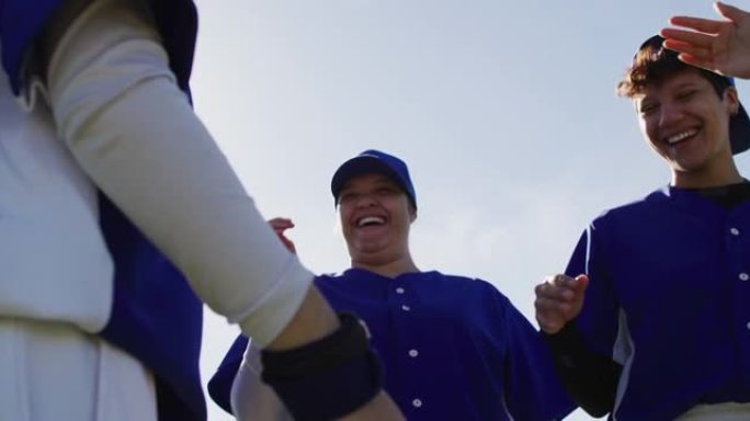 快乐的多元化女子棒球运动员在赛后交谈和击掌