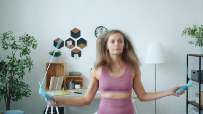 现代公寓中时髦运动服用跳绳锻炼的苗条女运动员肖像