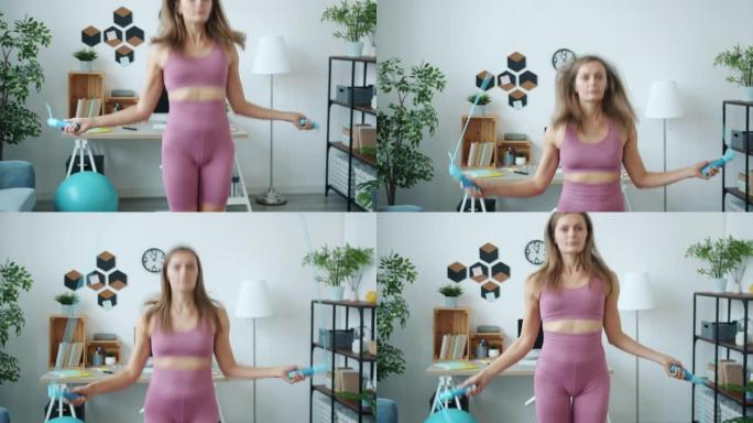 现代公寓中时髦运动服用跳绳锻炼的苗条女运动员肖像