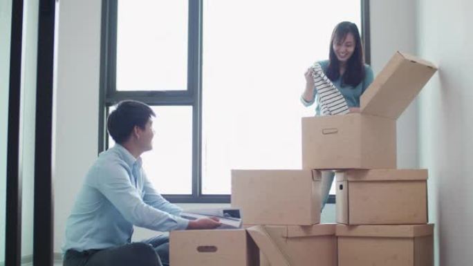 年轻的亚洲男女在新家中打开包装盒