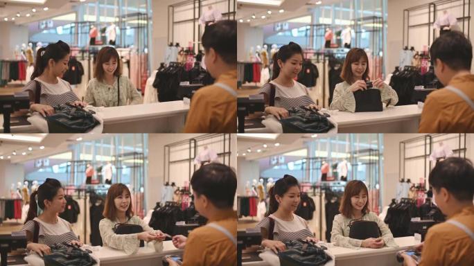 亚洲华人服装店收银员在柜台收到顾客的信用卡