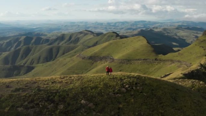 站在南非夸祖鲁-纳塔尔省壮观的德拉肯斯堡山脉顶上的游客的空中平移视图