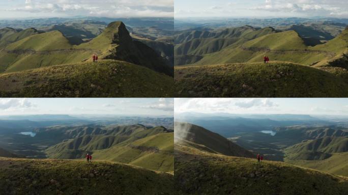 站在南非夸祖鲁-纳塔尔省壮观的德拉肯斯堡山脉顶上的游客的空中平移视图