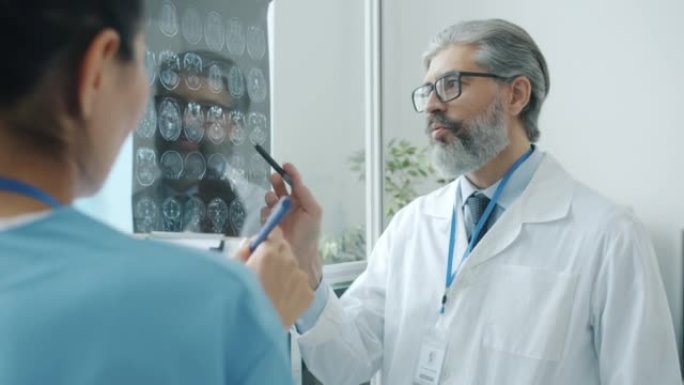 穿着制服的医生和护士在医院里看着脑部扫描讨论诊断