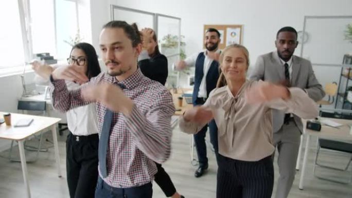 快乐上班族一起跳舞的慢动作在工作场所微笑着移动的手臂