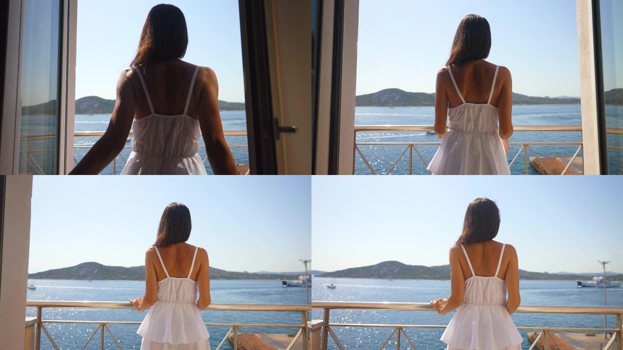 一名年轻女子的真实照片是在暑假假期旅行期间从酒店房间的露台上乘坐游艇在大海上欣赏全景。