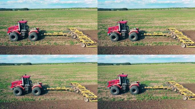 一辆拖拉机骑在一块田地上，耕种它。