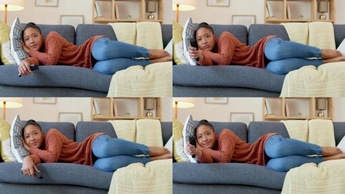 无聊的女人看电视，感到沮丧。年轻的非洲妇女躺在沙发上用遥控器在家放松。选择一个能让你开心的网络订阅计