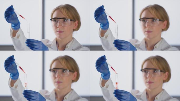 穿着白大褂的女实验室工作人员将红色液体从移液管中注入试管