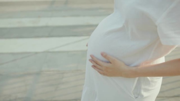 孕妇在公园摸她的大肚子。