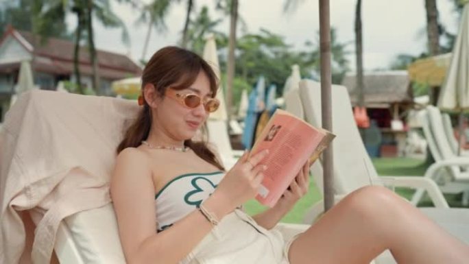 亚洲年轻女子在热带岛屿上放松时看书。
