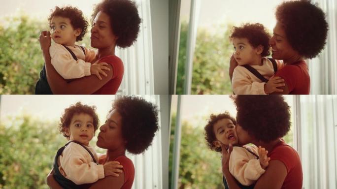 慈爱的母亲在现代家庭客厅拥抱可爱的男婴。开朗的妈妈亲吻和养育她的孩子。童年、新生活、为人父母的概念。