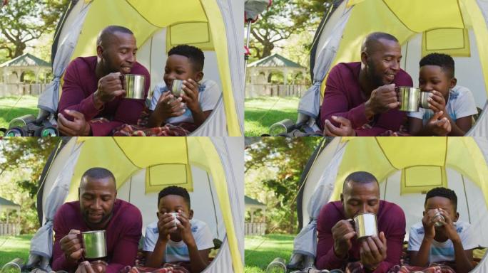 非裔美国人爸爸和儿子在花园里的帐篷里一起敬酒和喝咖啡