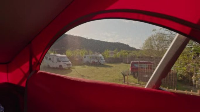 从露营车的一楼看，带窗户的红色屋顶，露营地上有很多货车，面包车生活