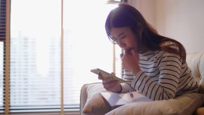 女人在家中使用手机扫描财务账单以进行在线支付