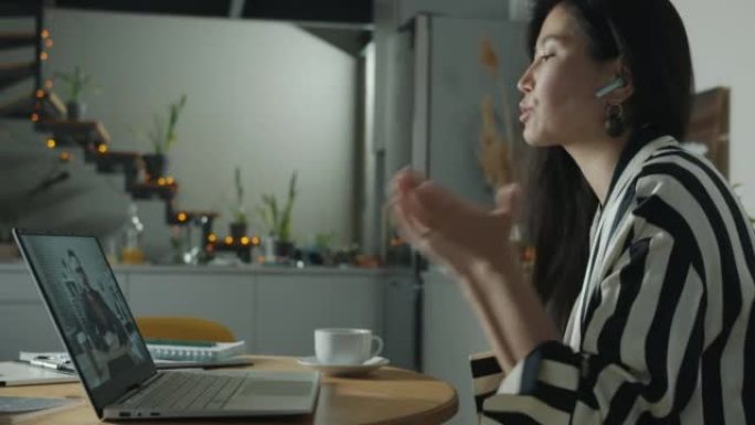 快乐的年轻女子使用笔记本电脑与男同事交谈，在家中进行在线视频通话