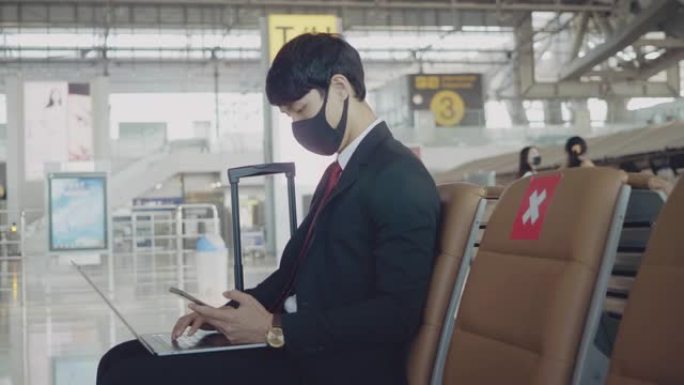 在机场用笔记本电脑工作的亚洲商人。