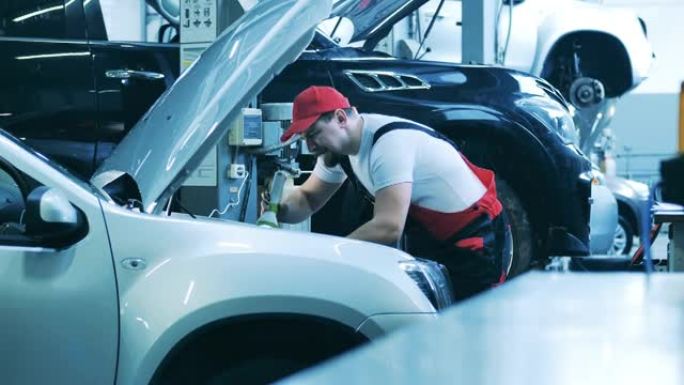 汽车修理工使用手电筒检查汽车内部。汽车维修公司的汽车修理工。