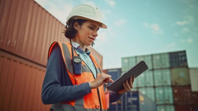 一位穿着白色安全帽的美丽拉丁女工业工程师的微笑肖像，在平板电脑上工作的高可见度背心。集装箱码头的检查