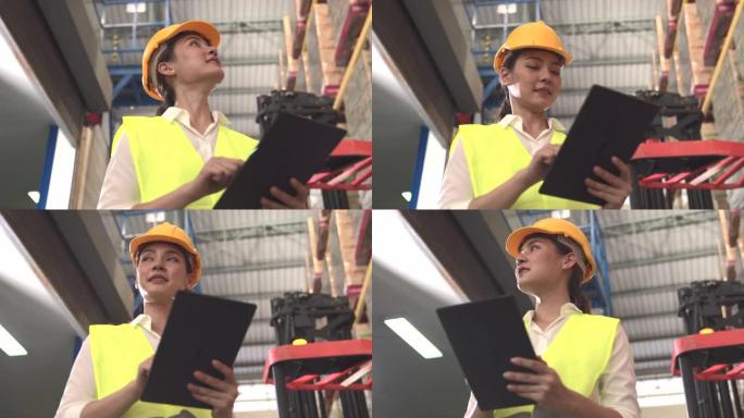 亚裔女工程师站在平板电脑上看着仓库货架。女人可以为男人工作，这意味着社会的平等。