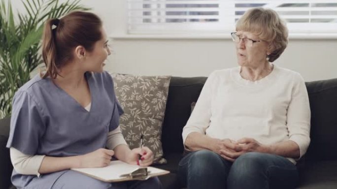 4k视频片段，一名女护士坐下来与一名老年患者进行咨询