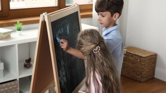 两个男孩和女孩用粉笔在游戏黑板上画画