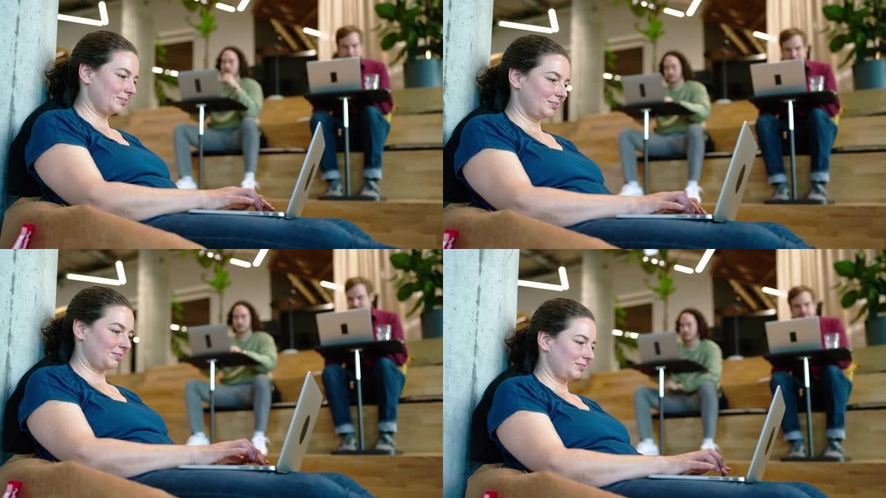坐在创意办公室台阶上的笔记本电脑上的女人