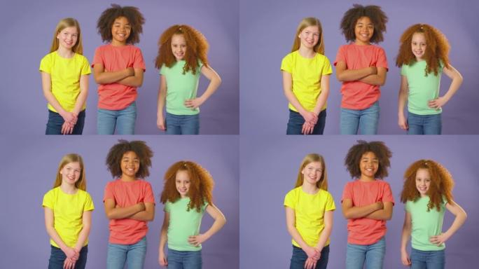 三个孩子朋友站在紫色背景下的工作室肖像照片-慢动作拍摄
