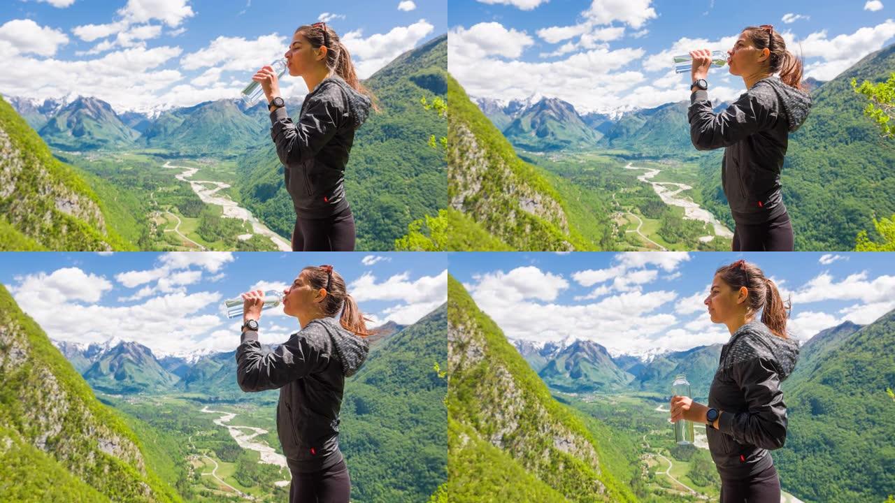 女人从山上徒步旅行中休息，用水瓶喝水